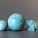 amazonite sphere with a smaller sphere and a stone bear figure on a gray background