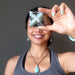Woman holding a amazonite star-shaped stone in front of her face against a dark background