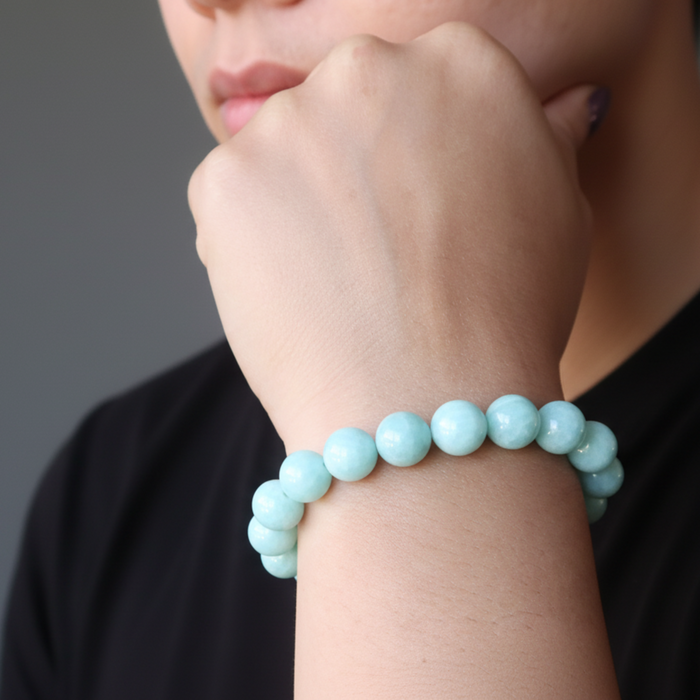 Person wearing a light blue beaded bracelet on a neutral background