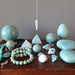 Collection of amazonite stones, beads, and a pendulum on a wooden surface with a gray background.