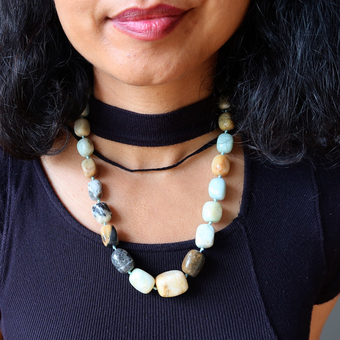 Person wearing a necklace with natural Amazonite stone beads against a dark background