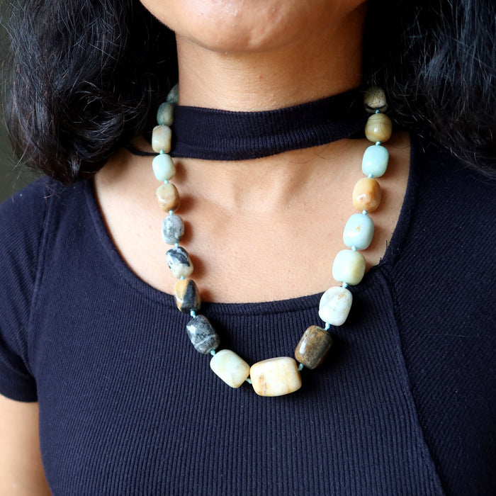 Amazonite Necklace with multicolored beads worn by a person against a dark background