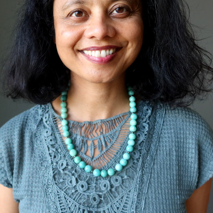 Woman wearing a blue lace top and Amazonite necklace against a neutral background
