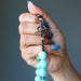 Hand holding a Amazonite beaded necklace against a gray background