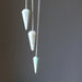 Three amazonite pendulums on silver chains against a dark background