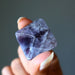 Hand holding a purple Amethyst crystal against a gray background