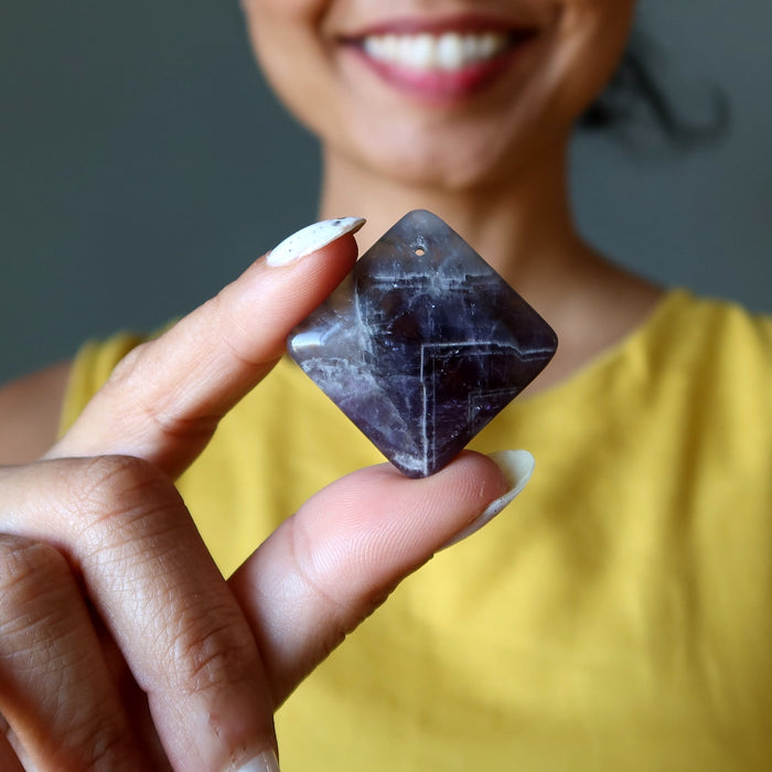 Person holding a dark Amethyst crystal with a blurred background