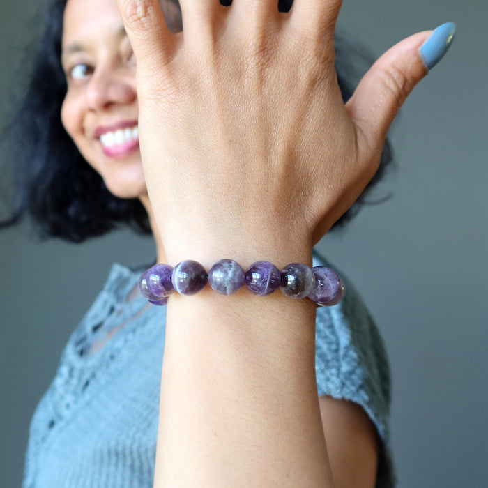 Woman wearing a chevron amethyst purple beaded bracelet with a blurred background