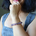 Person wearing a purple Amethyst bracelet on their wrist