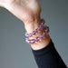 Purple amethyst beaded bracelet on a wrist against a gray background