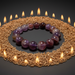 Purple beaded bracelet on a circular arrangement of grains with candles around it