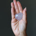 Hand holding a heart-shaped amethyst crystal against a dark background
