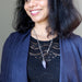 Woman wearing a dark blue cardigan and black top with an amethyst  necklace featuring a purple pendant.