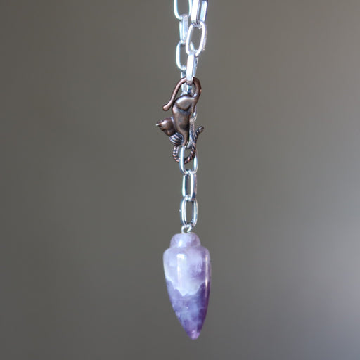 Necklace with a purple amethyst pendant and cat figure on a blurred background