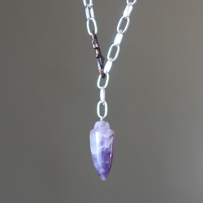 Necklace with a purple amethyst  crystal pendant on a plain background