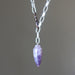 Necklace with a purple amethyst  crystal pendant on a plain background