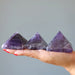 three amethyst pyramids in hand