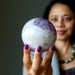 woman holding light purple amethyst sphere