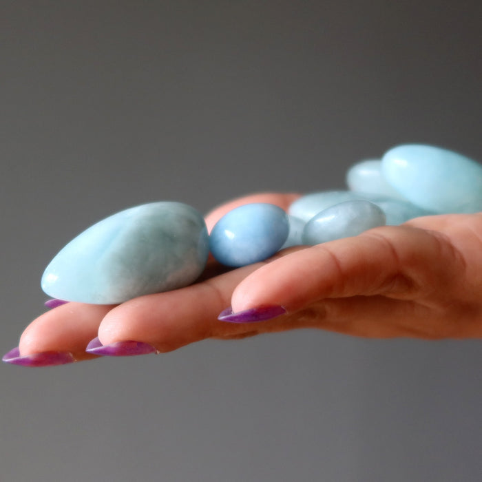 blue aquamarine tumbled stones in hand