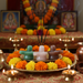 Decorative altar with shivling stones, flowers, and candles on a tablecloth.