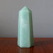 Green Aventurine crystal pyramid on a wooden surface with a neutral background