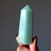 Green Aventurine crystal held by a hand against a dark background