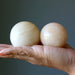 two yellow aventurine spheres in palm of hands