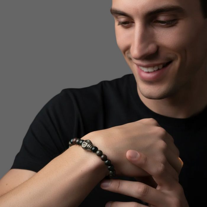 Man wearing a black beaded bracelet on a gray background