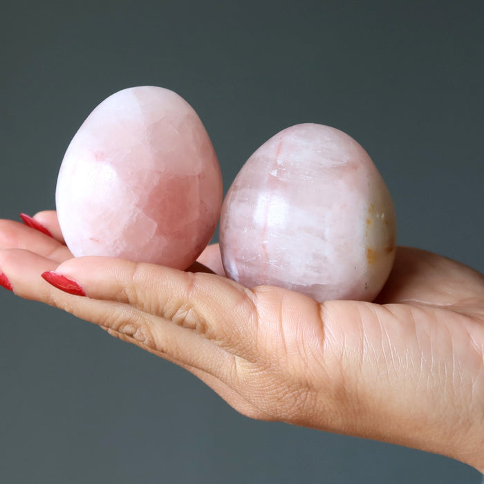 pink calcite eggs in hand