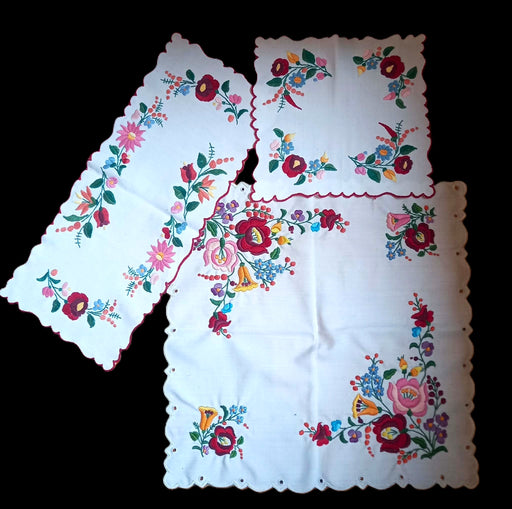 Embroidered Hungarian kalocsa floral design on a white fabric table set against a black background