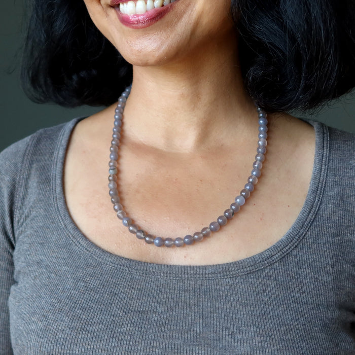 Woman wearing a gray chalcedony necklace against a neutral background
