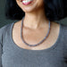 Woman wearing a gray chalcedony necklace against a neutral background