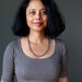 Woman wearing a gray top and gray chalcedony necklace against a dark background