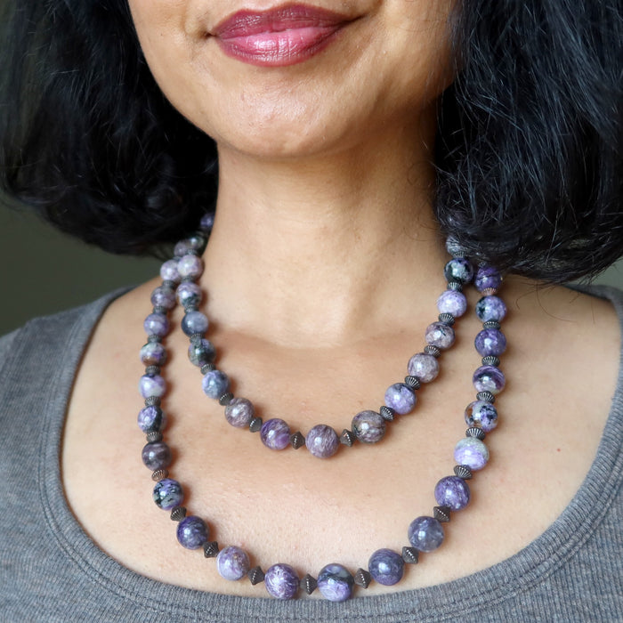 Close-up of a woman wearing a purple  charoite beaded necklace.