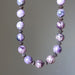 Necklace with purple charoite beads and silver accents on a neutral background