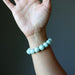 Hand wearing a Green Chrysoprase beaded bracelet against a dark background