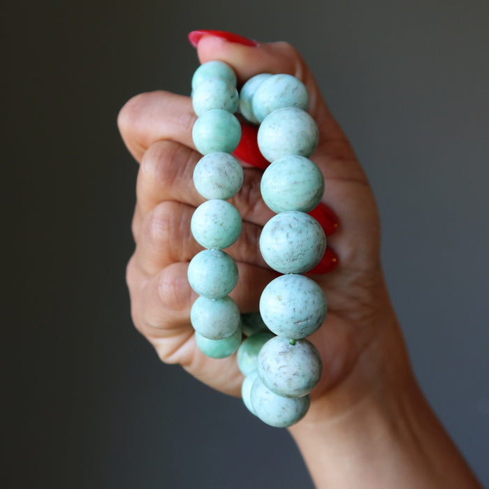 Hand holding a Green Chrysoprase beaded bracelet against a neutral background
