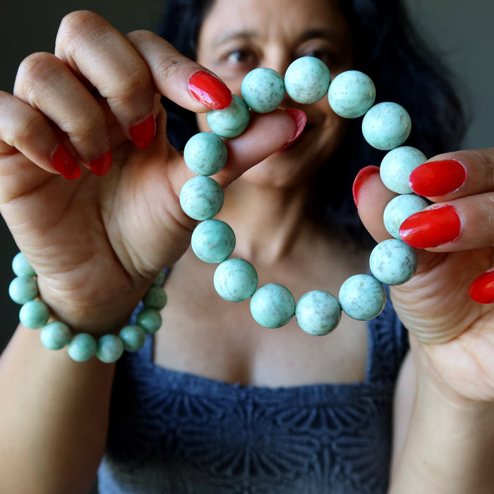 Person holding a Green Chrysoprase beaded bracelet with a blurred background