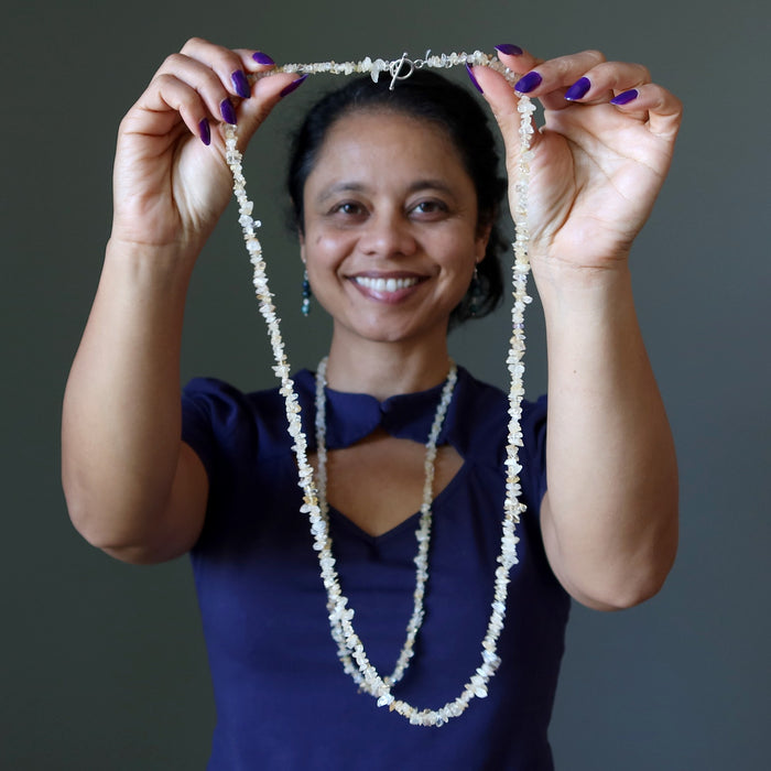 woman wearing and holding citrine necklaces