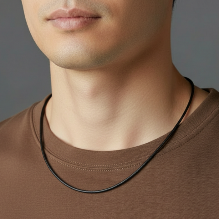 Man wearing a brown shirt with a black necklace against a gray background