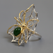 Gold and silver spider ring with a green stone on a white background