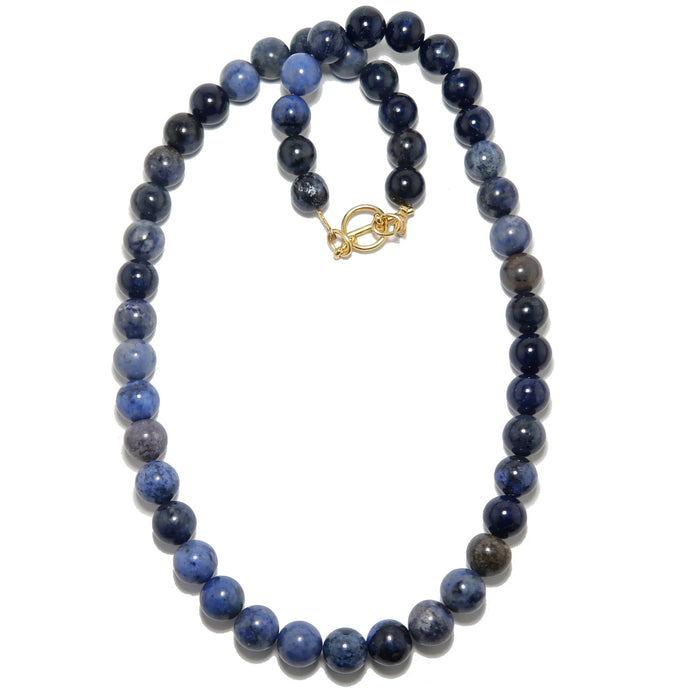Necklace with blue dumortierite beads and a gold clasp on a white background