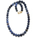 Necklace with blue dumortierite beads and a gold clasp on a white background