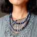 blue dumortierite beaded necklaces worn by a person against a gray lace garment.