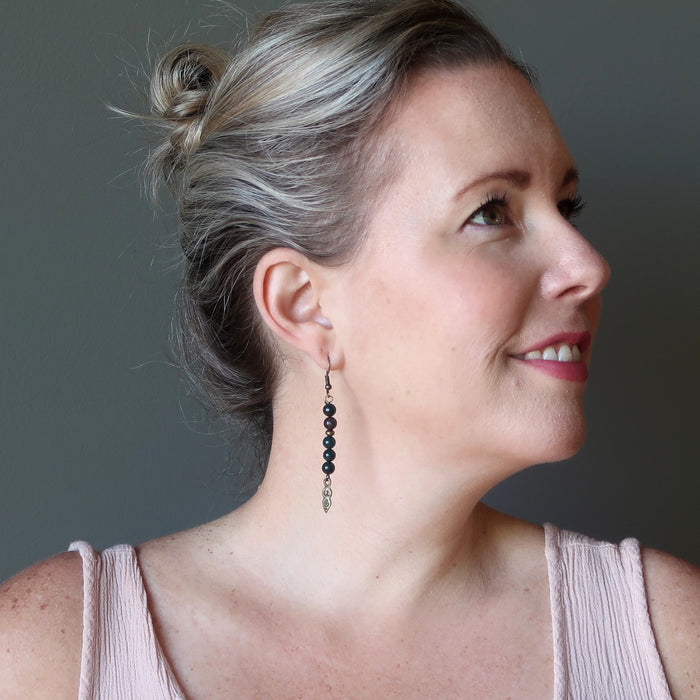 Woman wearing a pink top and bloodstone earrings with a neutral background