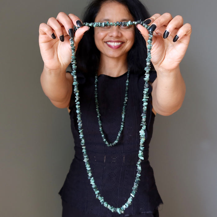 model holding and wearing  emerald necklaces