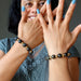 woman wearing two hawks eye and gold beaded stretch bracelets