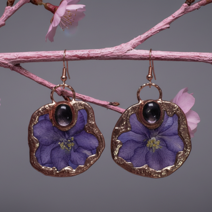 Pair of earrings with purple floral design on a branch with pink flowers.
