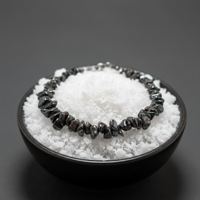 Black Hematite bracelet on a bed of white stones in a black bowl against a dark background