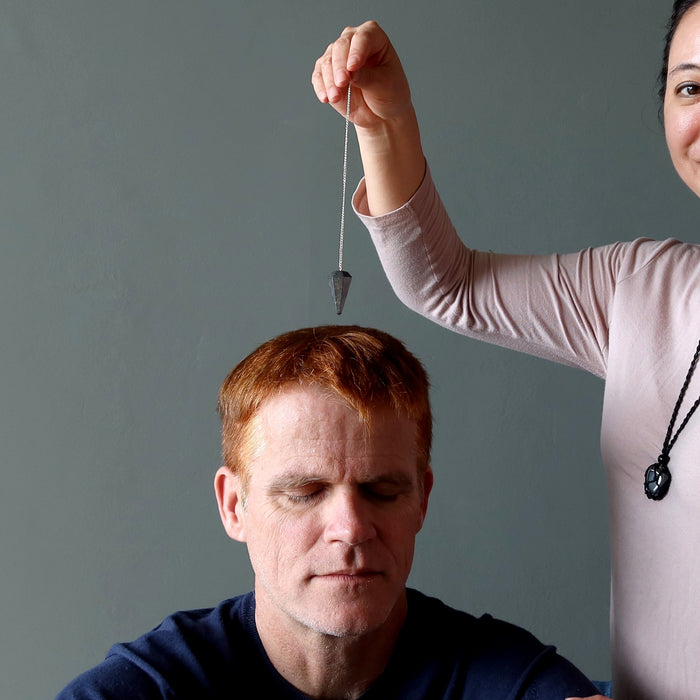 dowsing with a hematite pendulum over man's head